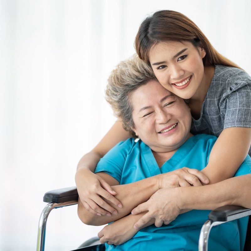 Asian daughter or care assistant helping support senior woman or mother